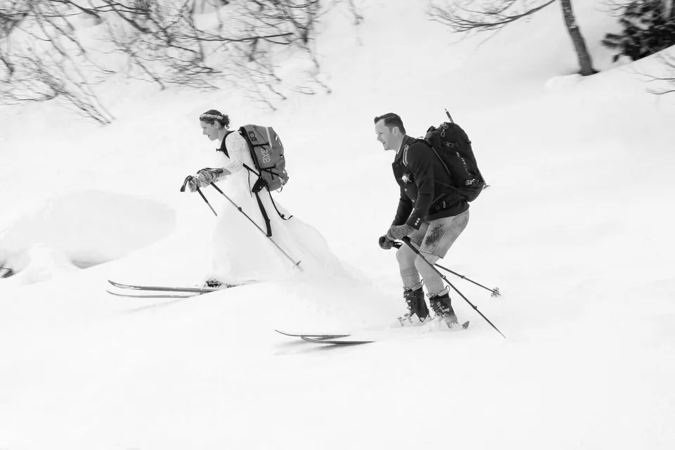 Brautpaar beim Skitouren durch tiefen Schnee in den Bergen