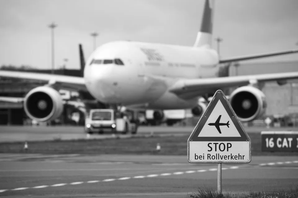 Schwarz-weiss Flughafenszene mit Stoppschild und Passagierflugzeug auf dem Rollfeld